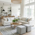 Modern living room with Cove white sectional, wooden coffee table, and large windows.