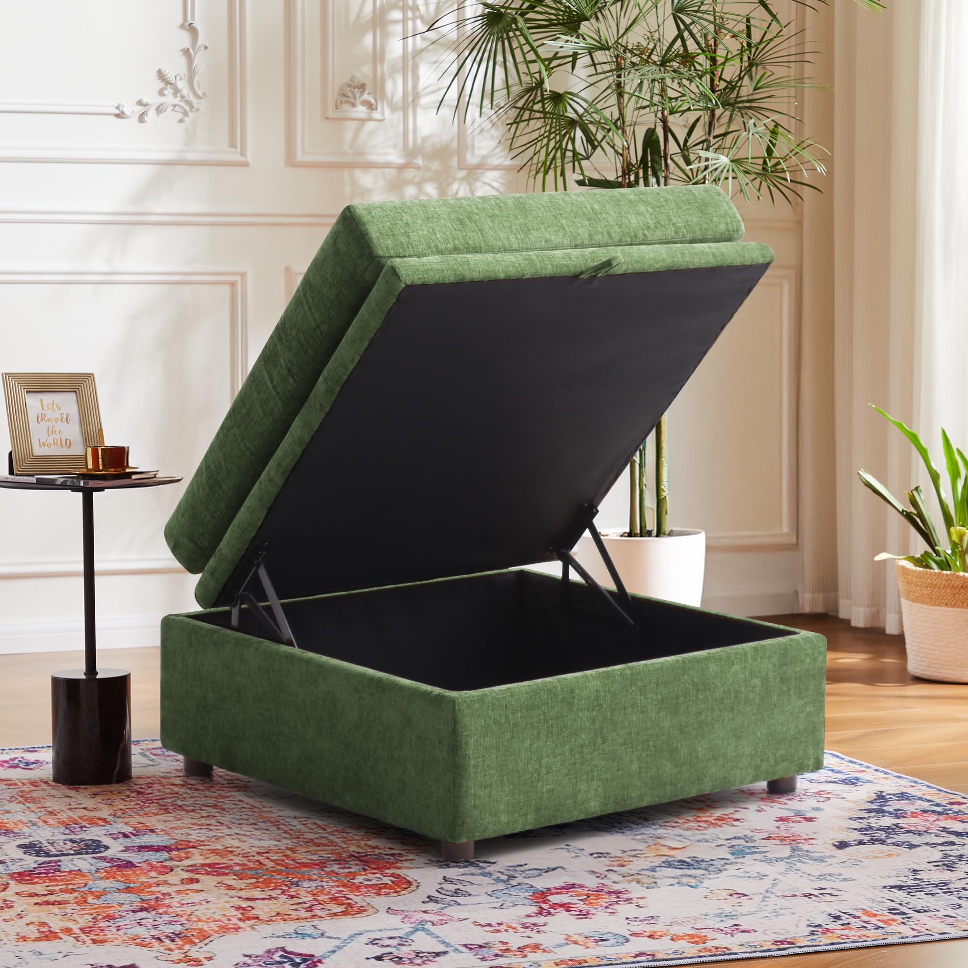 Green upholstered Huddle storage ottoman in a living room setting with plants and a small table.